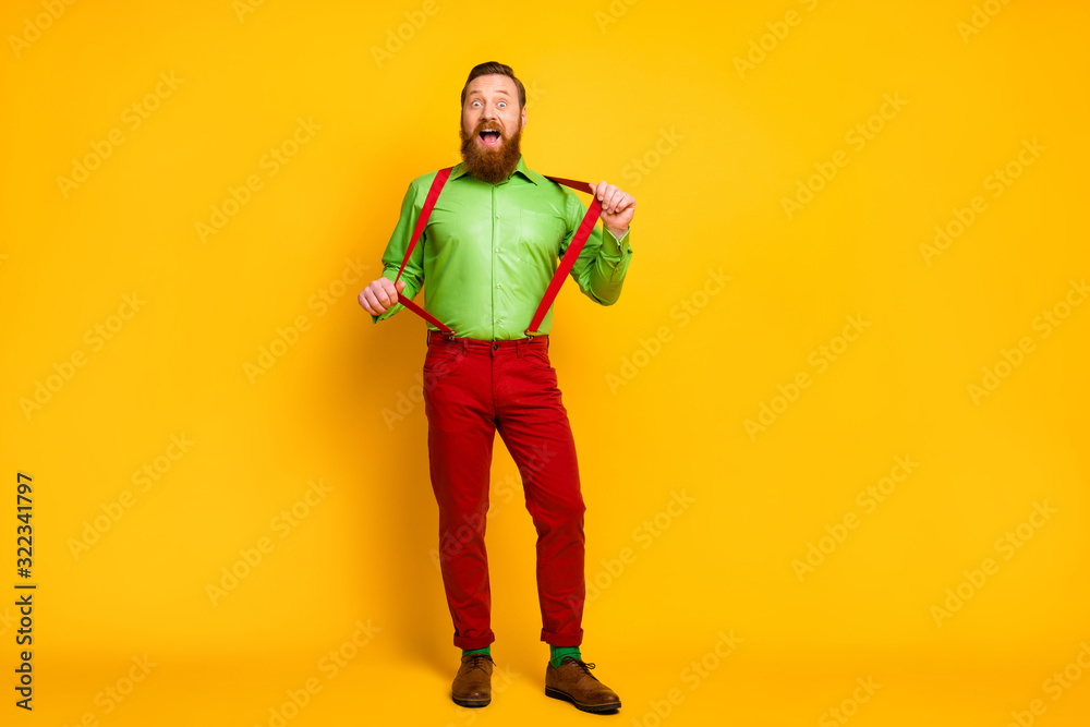 Full body photo of attractive funny guy model good mood playful macho wear green shirt red suspenders pants socks footwear isolated vibrant color background Full body photo of attractive funny guy model good mood playful macho wear green shirt red suspenders pants socks footwear isolated vibrant color background