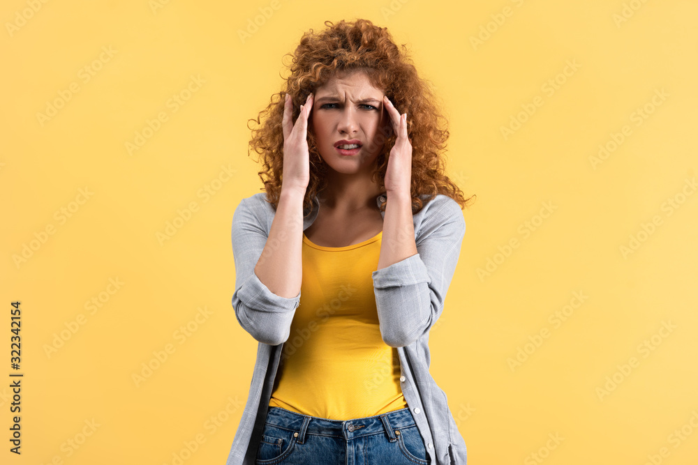 stressed redhead girl having headache isolated on yellow