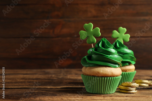 Fototapeta Naklejka Na Ścianę i Meble -  Delicious decorated cupcakes on wooden table, space for text. St. Patrick's Day celebration