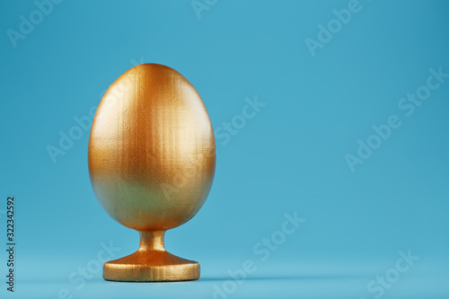 Golden egg on a blue background with a minimalistic concept. Space for text. Easter egg design templates. Stylish decor with minimal concept.