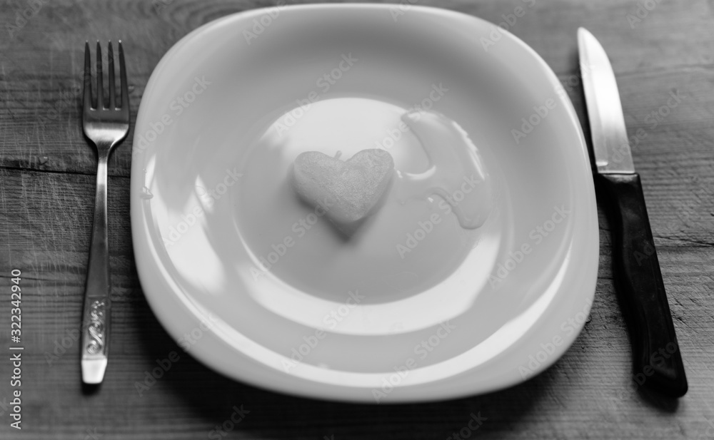 A snowy heart melts on a white plate. Heart shaped snow on a saucer. Ice in frosty weather. Melted water is collected in a small puddle. Wooden background. Love on valentine's day concept A snowy heart melts on a white plate. Heart shaped snow on a saucer. Ice in frosty weather. Melted water is collected in a small puddle. Wooden background. Love on valentine's day concept