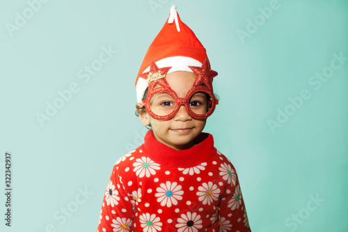 Sweet little girl wearing christmas glasses in santa hat