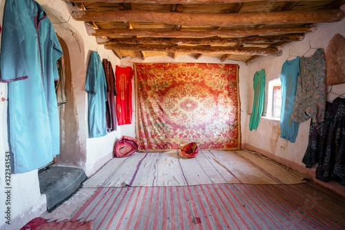 Interior of a historic room decorated with Berber carpet and clothes in Ait Ben Haddou, Morocco