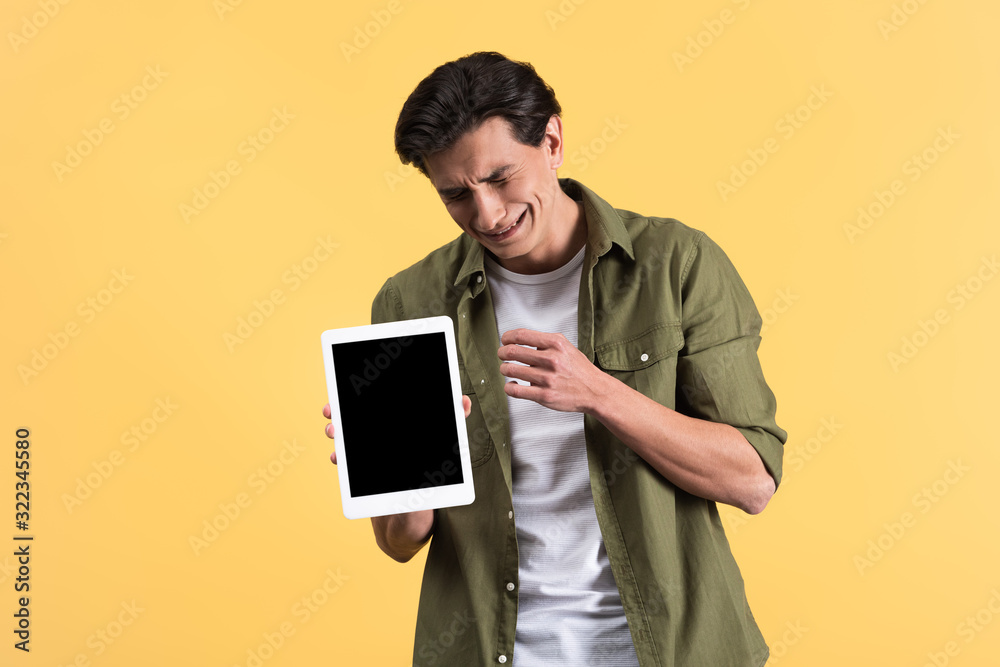 crying man showing digital tablet with blank screen, isolated on yellow crying man showing digital tablet with blank screen, isolated on yellow