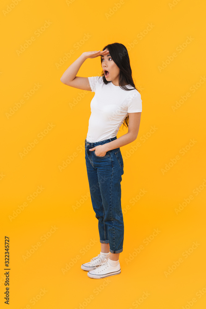 Full length image of young brunette asian woman looking in distance