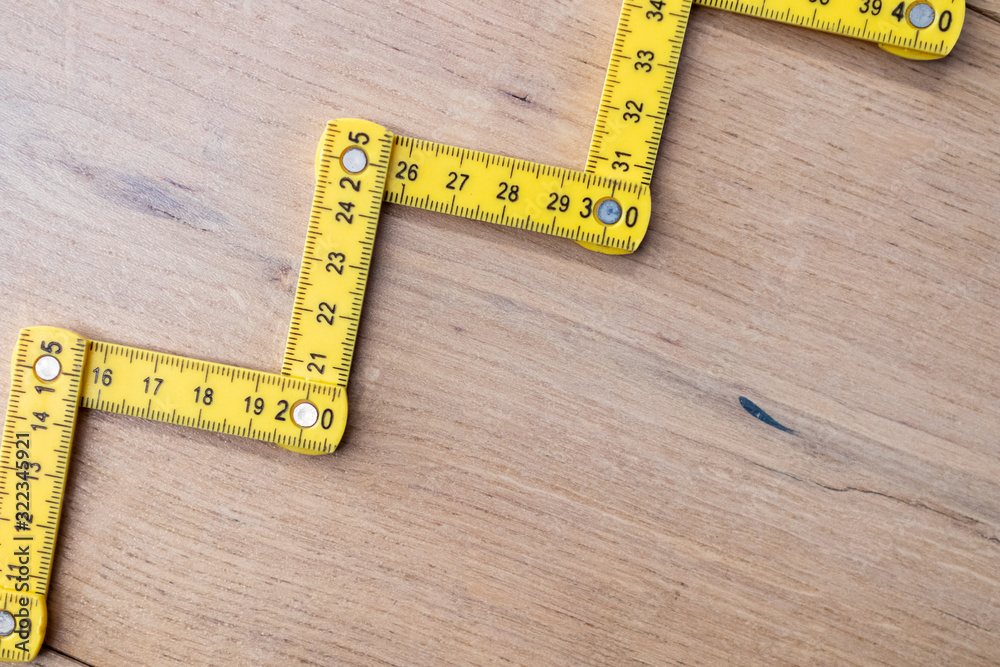 Folding zig zag ruler. Measuring tape folding yellow open in zigzag tips on a workbench. Measuring tools for carpenters and bricklayers. Measurement for building renovations of houses and apartments Folding zig zag ruler. Measuring tape folding yellow open in zigzag tips on a workbench. Measuring tools for carpenters and bricklayers. Measurement for building renovations of houses and apartments