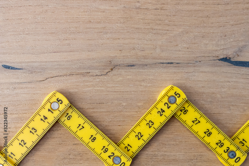 Folding zig zag ruler. Measuring tape folding yellow open in zigzag tips on a workbench. Measuring tools for carpenters and bricklayers. Measurement for building renovations of houses and apartments Folding zig zag ruler. Measuring tape folding yellow open in zigzag tips on a workbench. Measuring tools for carpenters and bricklayers. Measurement for building renovations of houses and apartments