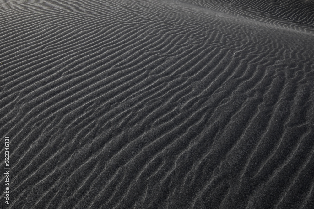 Black Icelandic Basalt Sand. Embossed sandy texture. Wavy background. Abstract pattern. Nature design. Reynisfjara beach with black volcanic sand. Stokksnes dunes. Reynisdrangar, Vik, Iceland Europe