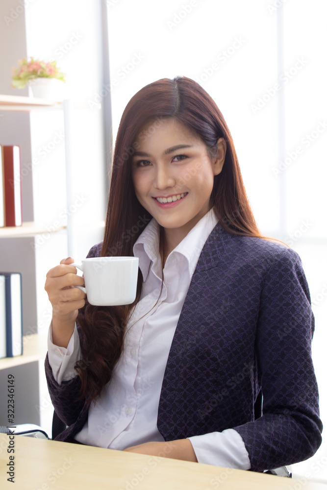Beautiful young asian business woman while drinking a hot beverage with smile and happy face. Concept of business woman and ready to work. Beautiful young asian business woman while drinking a hot beverage with smile and happy face. Concept of business woman and ready to work.