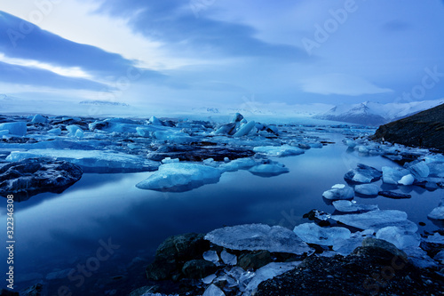 iceland glacier jokulsarlon in the evening icebergs floating on the cold peaceful water after sunset with dramatic sky .