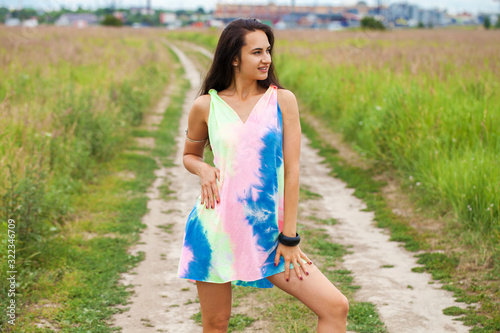 Foto Young beautiful woman in colored tunic posing against the background of a meadow