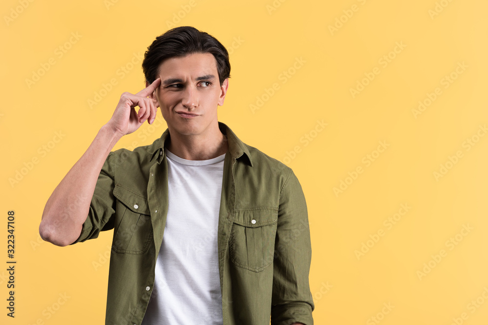 skeptical brunette young man thinking isolated on yellow skeptical brunette young man thinking isolated on yellow