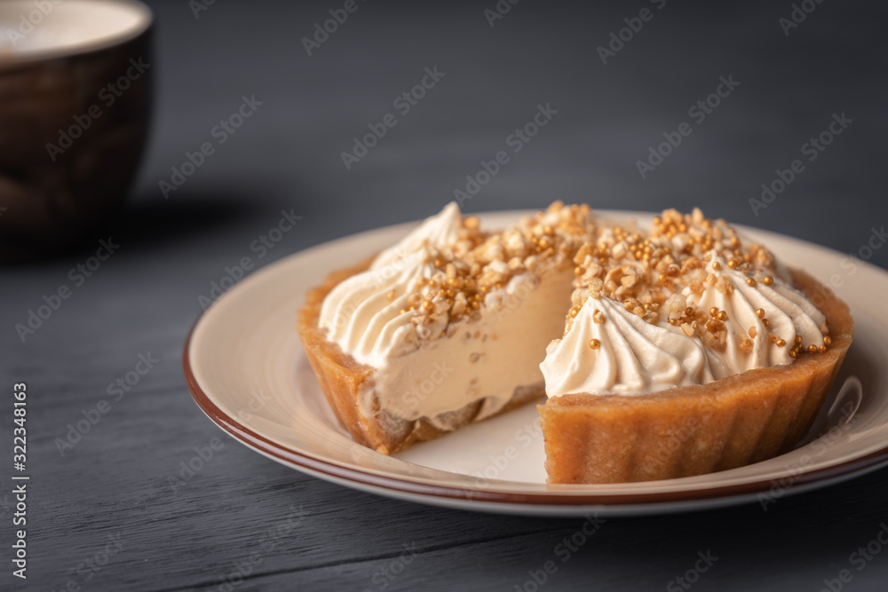 Cut cake basket with caramel near cappuccino on black wooden background. Cut cake basket with caramel near cappuccino on black wooden background.