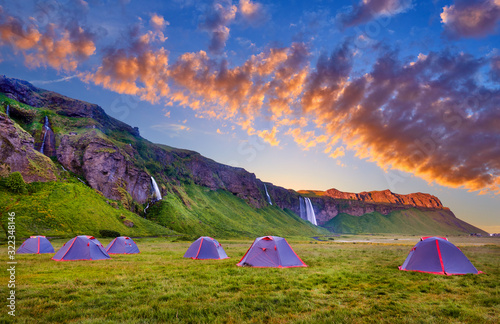 Camping tents near Seljalandsfoss. One of the most beautiful waterfalls on the Iceland, Europe. Popular and famous tourist attraction summer holiday destination in on South Iceland. Travel postcard.