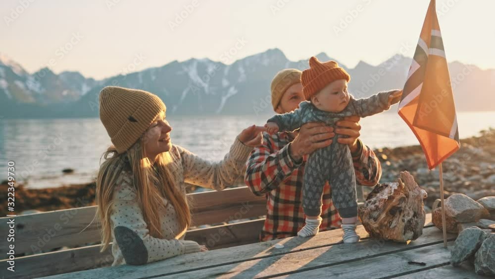 Family mother and father with baby traveling together in Norway vacation outdoor child learning norwegian flag healthy lifestyle mountains landscape 