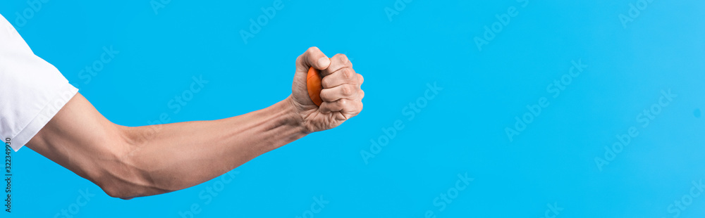 panoramic shot of irritated man squeezing stress ball in hand, isolated on blue panoramic shot of irritated man squeezing stress ball in hand, isolated on blue