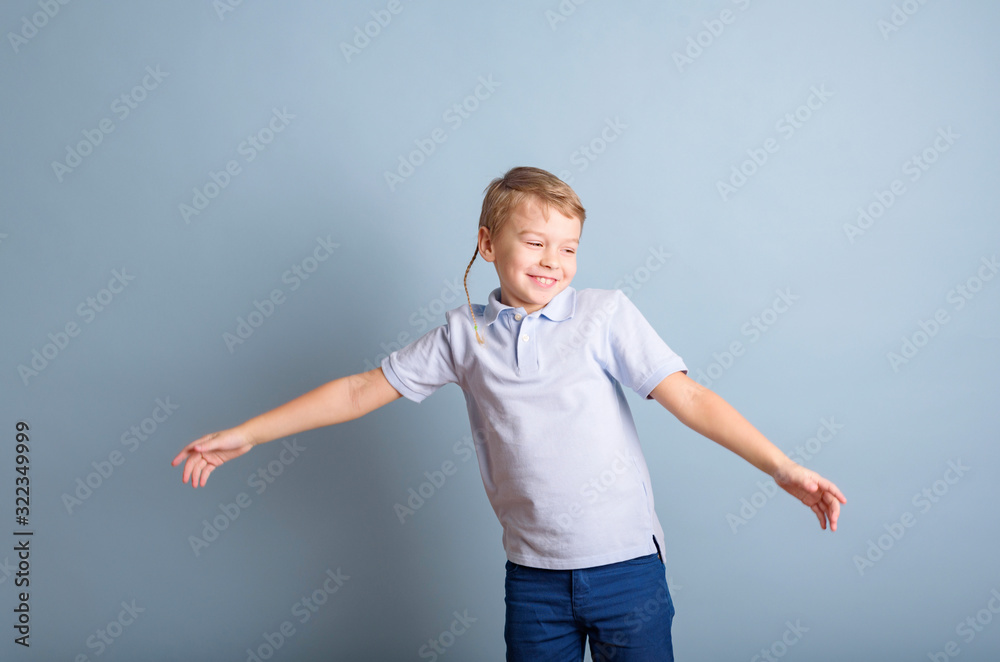 positive blond boy having fun on a blue background, the concept of a happy and joyful childhood positive blond boy having fun on a blue background, the concept of a happy and joyful childhood