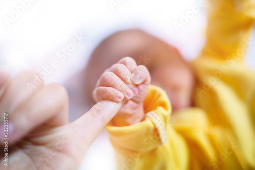 Newborn baby touching his mother hand, Baby holding finger of his mother giving senses of attachment and bonding. The image taken with a selective focus stressing an emotional scene. photo