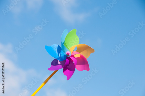 Colorful toy windmill on the background of a bright blue sky. The colors of the rainbow.