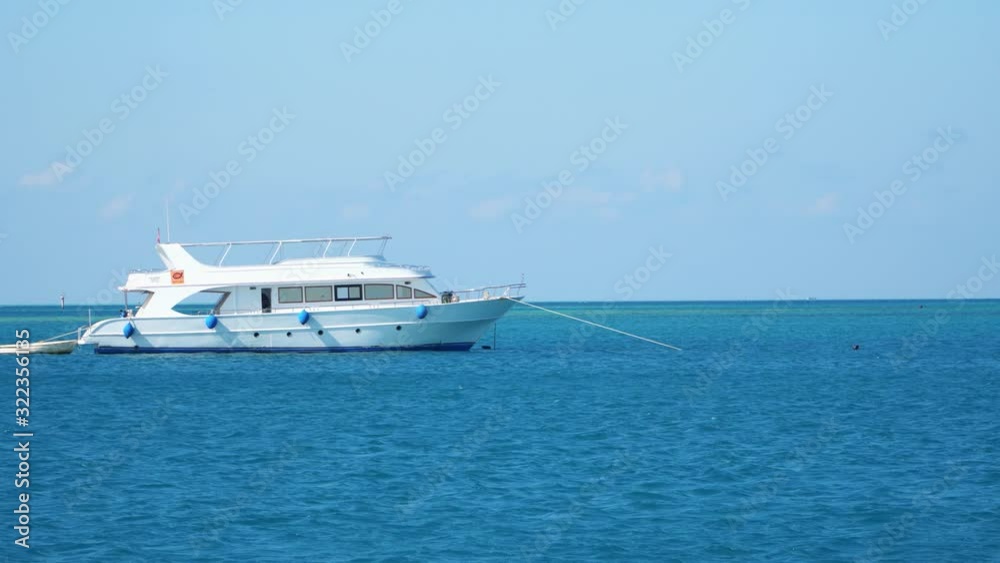 White yacht anchored in the sea. View from a floating ship. White yacht anchored in the sea. View from a floating ship.