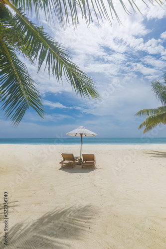 Cloudy tropical beach. Vacation landscape, two loungers and umbrella. Clouds with soft blue sky. Idyllic beach view, exotic travel destination