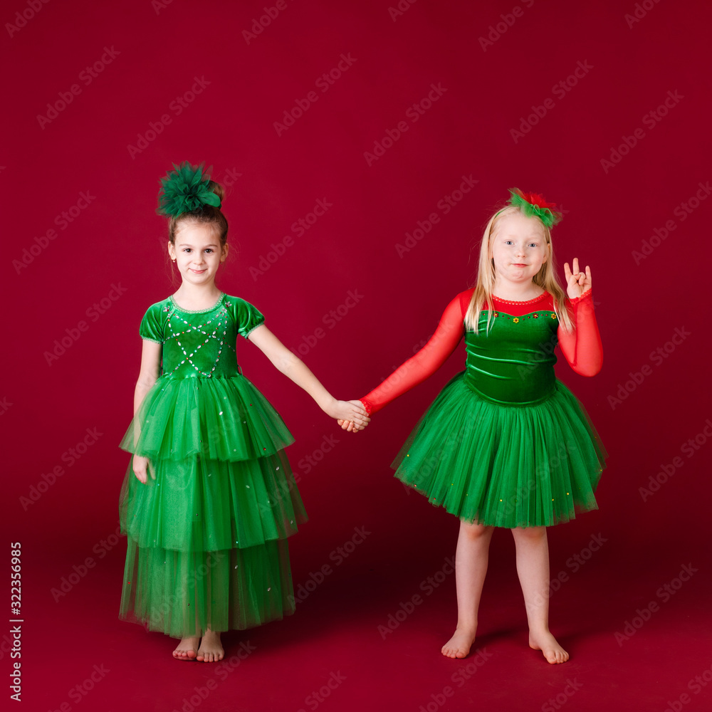 Beautiful little girl princesses dancing in luxury green dress isolated on red background. Carnival party with costumes Beautiful little girl princesses dancing in luxury green dress isolated on red background. Carnival party with costumes