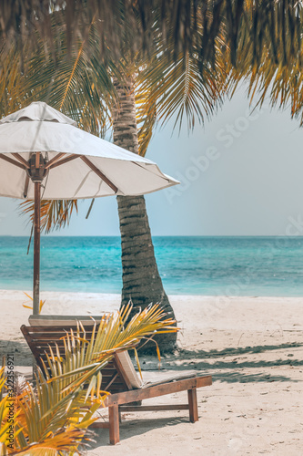 Fototapeta Naklejka Na Ścianę i Meble -  Tranquil beach scene, chairs and umbrella with palm tree and beautiful sea view. Summer vacation holiday concept design, vintage style effect