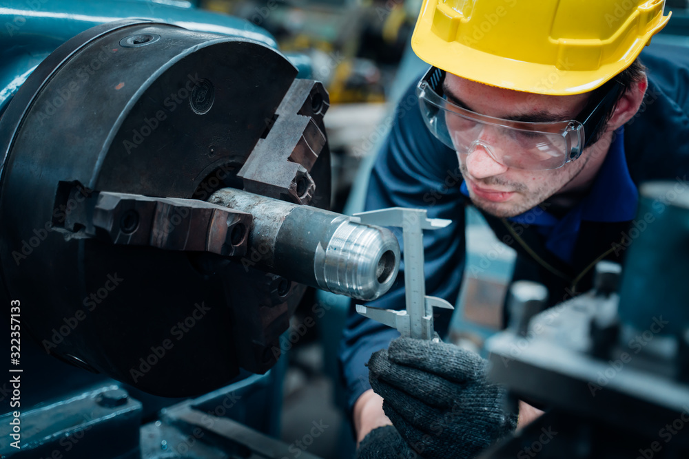 Fototapeta premium Work at the Heavy Industry Manufacturing Facility concept.Worker measuring on industrial turning machine with precision at factory.Man operating CNC drilling and boring machine in Industry.