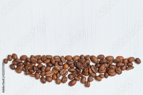 An abstract dish of coffee beans for copy space on a white wooden background.