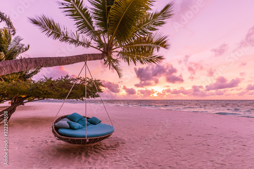 Tropical sunset beach background as summer landscape panorama with beach swing or hammock and white sand and calm sea beach banner. Perfect beach scene vacation or summer holiday concept © icemanphotos