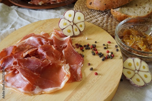  A snack of prosciutto, cereal ciabatta and homemade onion marmalade, served with fresh garlic and colorful pepper
