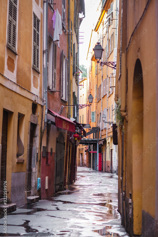 Fototapeta premium Narrow street in Nice, old colorful buildings in the old town, French Riviera