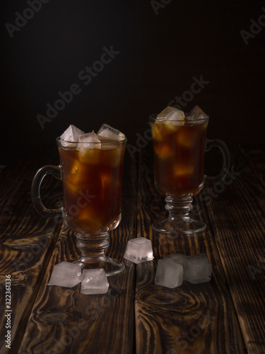 coffee drink with ice in a glass mug on a wooden background.