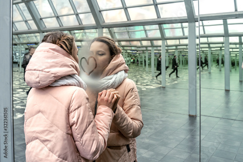 teen girl draws a heart on a mirror with many reflections, recursion. the theme of loneliness in the big city