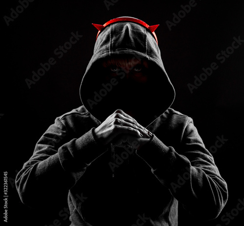 Shooting in the Studio. The girl in the hood holds her hands in front of her. Artificial horns on the head.