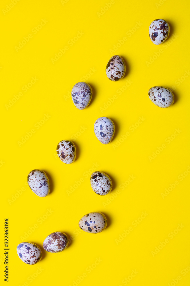 Group of quail eggs on yellow background. Copy space. Top view. Eco organic healthy products. Uncooked small natural fresh eggs. Vertical photo Group of quail eggs on yellow background. Copy space. Top view. Eco organic healthy products. Uncooked small natural fresh eggs. Vertical photo