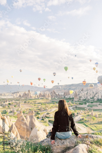 Woman watching colorful hot air balloons flying over the valley at Cappadocia, Turkey.Turkey Cappadocia fairytale scenery of mountains