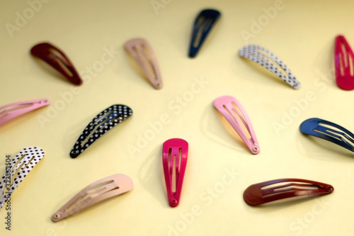 Colorful trendy hair clips on bright yellow background. Selective focus.