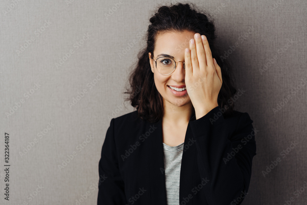 Young woman covering one eye with her hand Young woman covering one eye with her hand