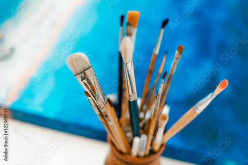 Tools and equipment for the artist. Palette and brushes close-up. The process of drawing and creativity. The picture is in blue.