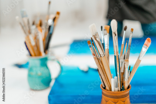 Tools and equipment for the artist. Palette and brushes close-up. The process of drawing and creativity. The picture is in blue.