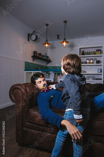 Canvas Print Little boy doing mischief to his father while sleeping on the couch