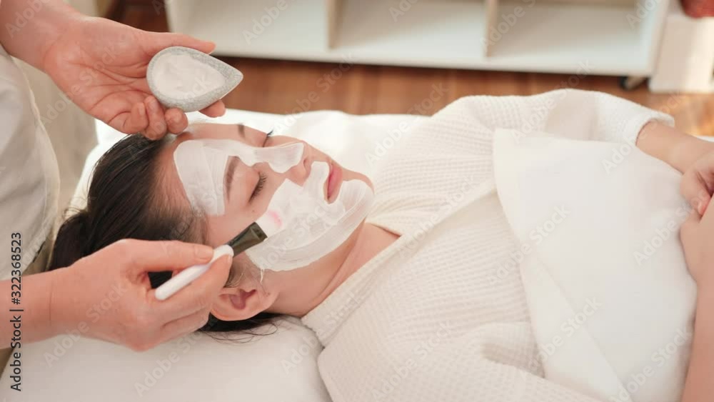 Close up Young Asian woman apply cream with brush mask on face in spa beauty salon. skin care and body care. Dolly slider Close up Young Asian woman apply cream with brush mask on face in spa beauty salon. skin care and body care. Dolly slider