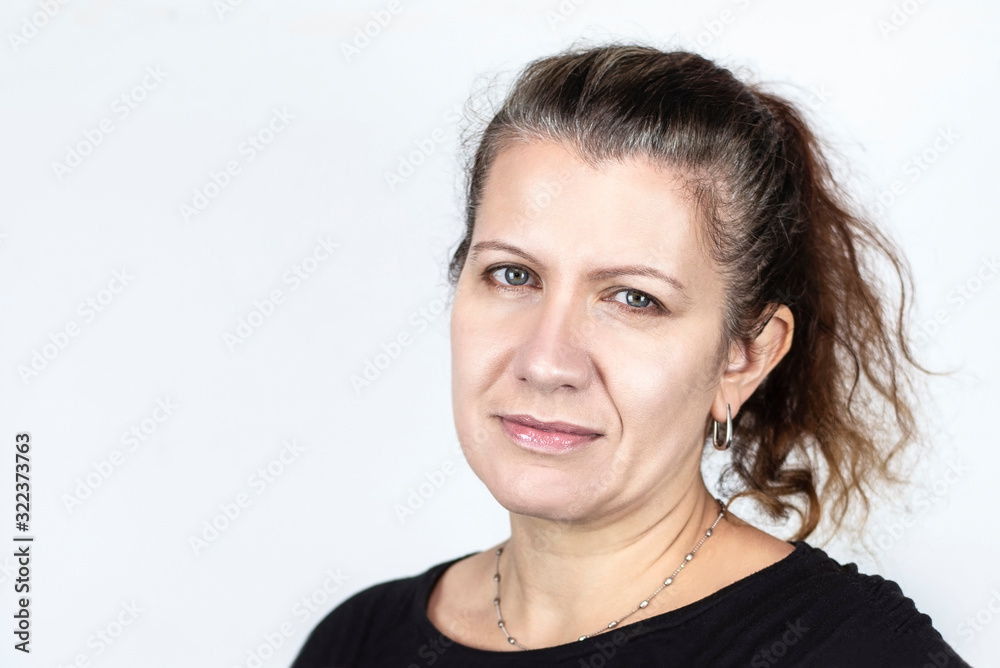 Portrait of happy middle aged woman on light background. A woman's hair is starting to turn gray and she is going to go to a hairdresser for a new hairstyle Portrait of happy middle aged woman on light background. A woman's hair is starting to turn gray and she is going to go to a hairdresser for a new hairstyle
