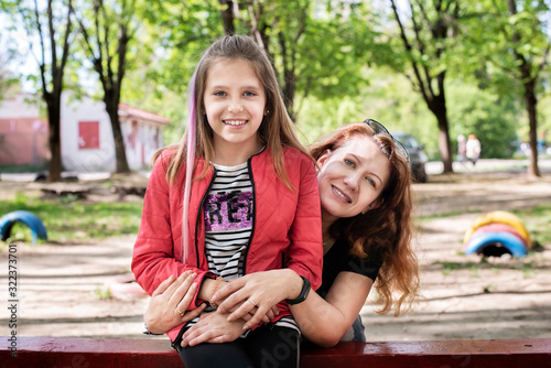 Authentic portrait of a young teenager girl and her mom. The daughter and mother had a serious conversation and are now taking pictures with delight photo