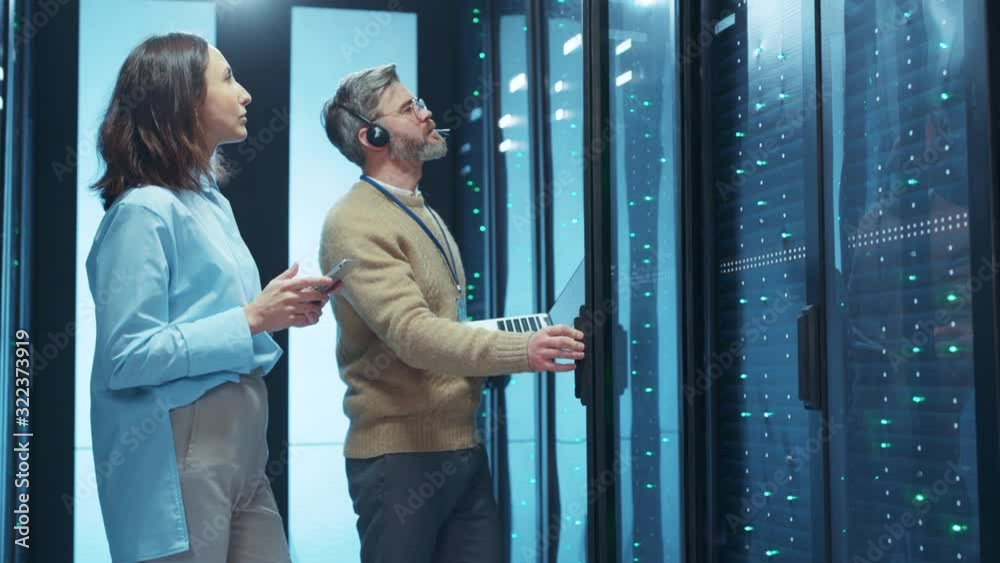 Couple of IT server technicians setting up and activating server cabinet in data center cooperating in business team. Database center.