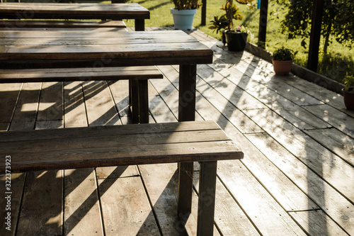 Gazebo in a roadside cafe with plants  wooden tables  benches and flowers around.