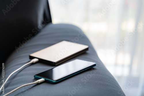 Cuadro en lienzo Mobile charging to smartphone from portable charger on Sofa..