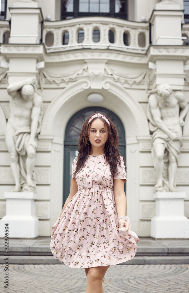 young beautiful bright girl in a summer dress walking down the street