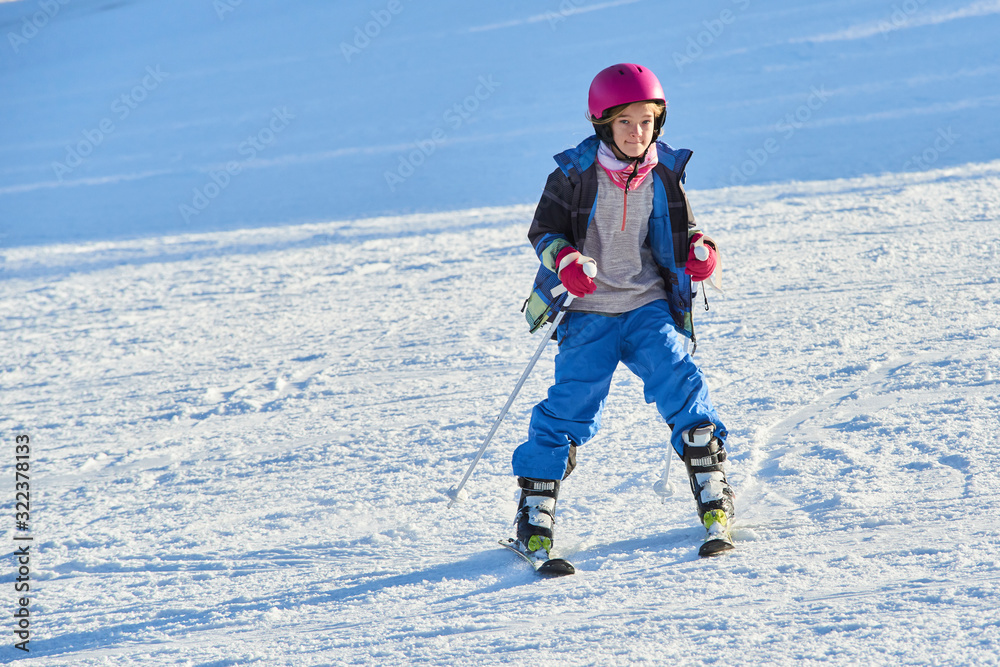 Child skiing in the mountains. Toddler kid in colorful suit and safety helmet learning to ski. Winter sport for family with young children.